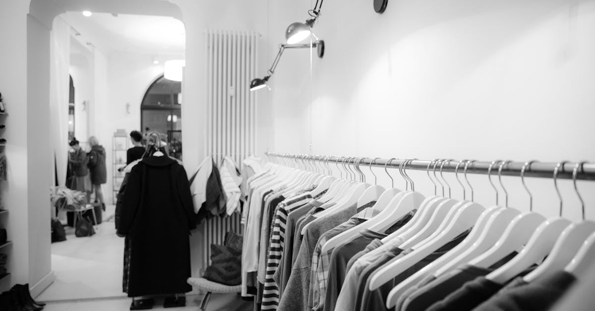 Stylish black and white interior of a boutique with clothes on racks, showcasing modern fashion.